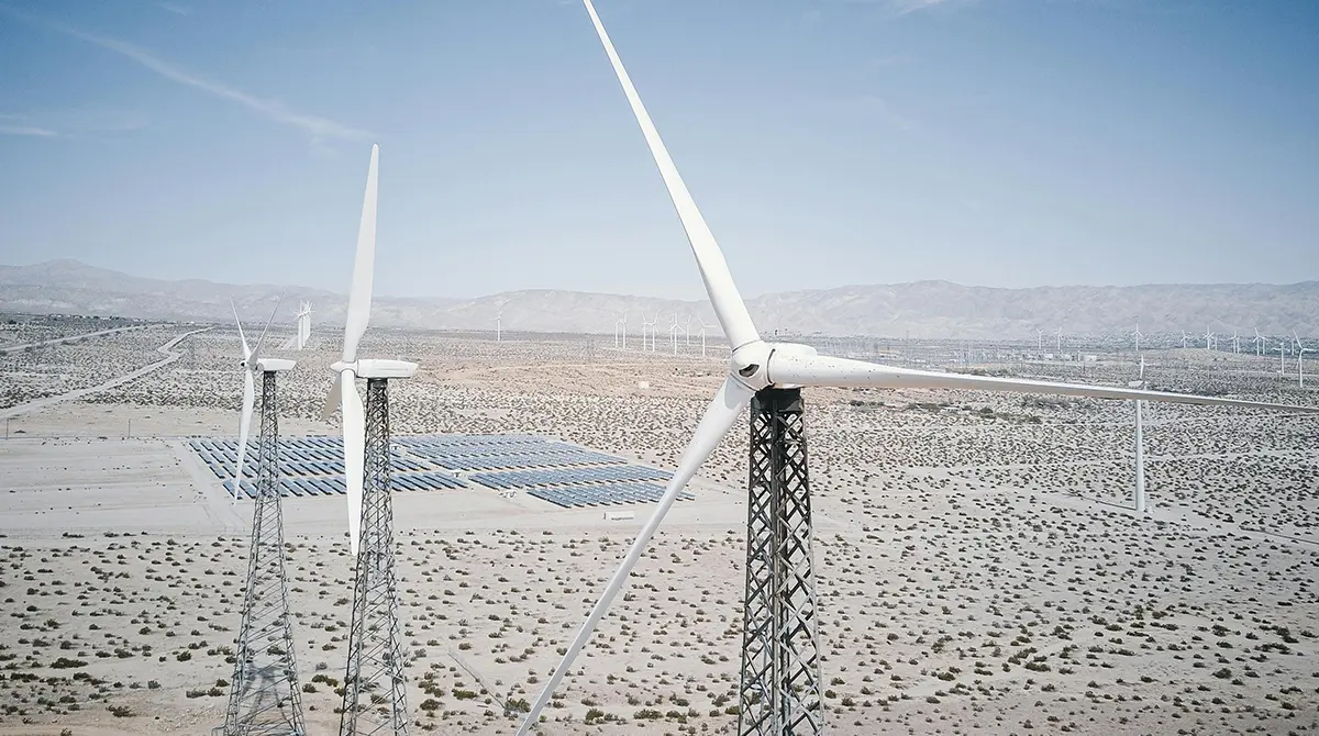 Vast integrated renewable energy and green hydrogen production facility in a desert with bifacial solar panels, wind turbines, concentrated solar power tower, electrolysis complex, hydrogen storage tanks, and transmission lines at golden hour. Yanma